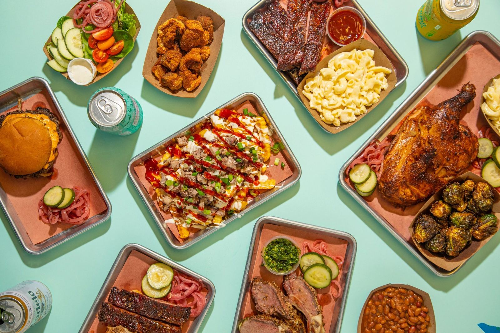 A table of Cochon King dishes: burger, wings, brisket, ribs, loaded fries, mac and cheese and a whole chicken