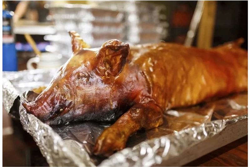 A whole smoked hog, glistening, on foil